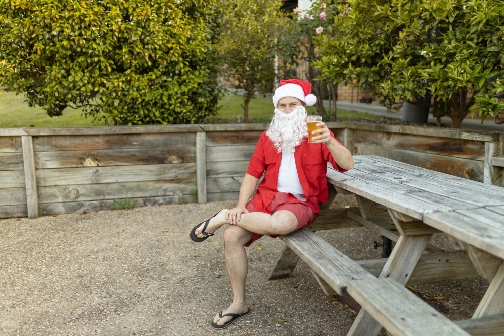 A Santa Claus at Christmas time in  the Australian summer holding a beer - Australian Stock Image