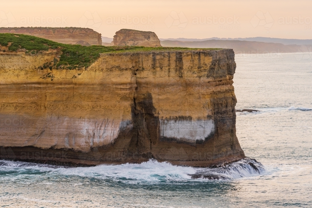 A sea cliff jutting out into the ocean high above the ocean at dawn - Australian Stock Image