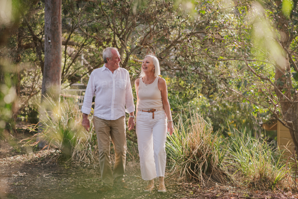 Image of A senior couple walks hand-in-hand along a garden path ...