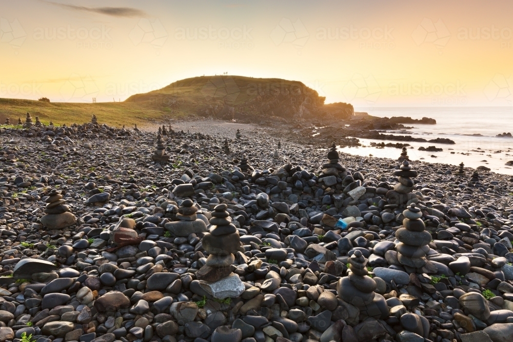 A series of rock piles on a rocky beach at sunrise - Australian Stock Image