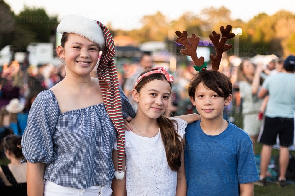 Image of a set of siblings in festive headwear at the carols - Austockphoto