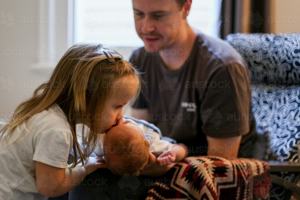 A sister kisses her newborn brother on the forehead - Australian Stock Image