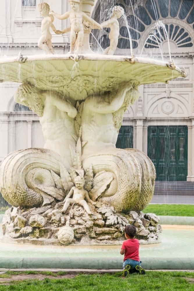 A small boy admires a large ornate fountain - Australian Stock Image