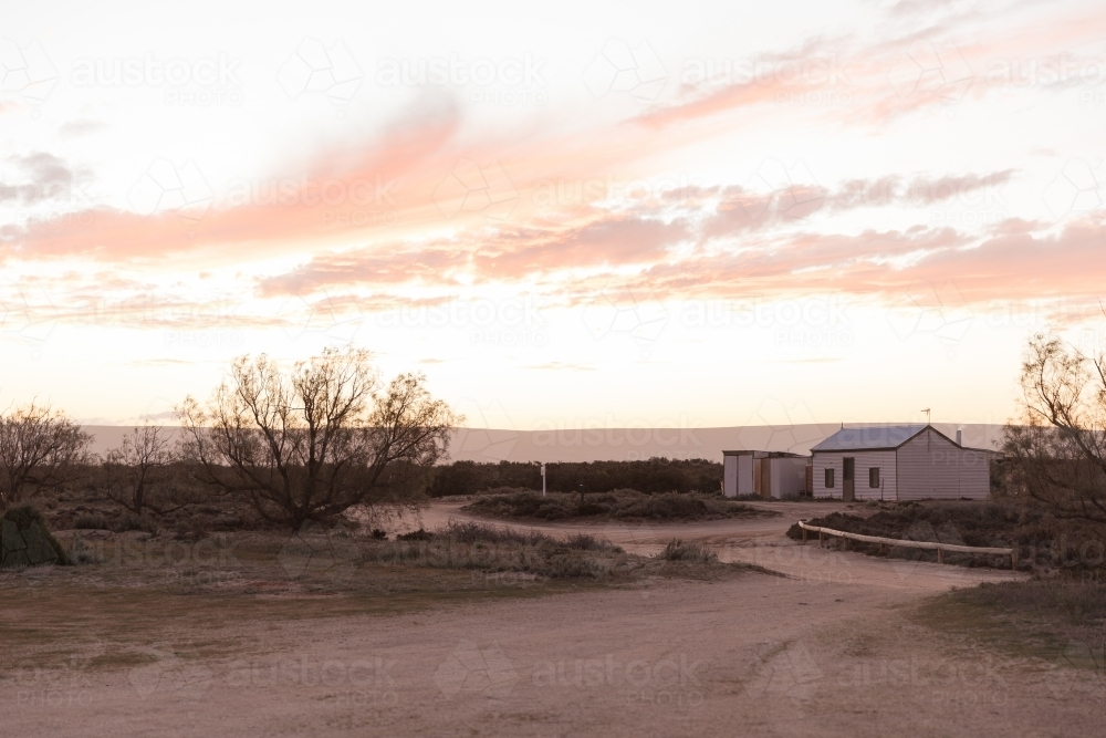 A small house under a cloudy sky with soft hues of pink and orange - Australian Stock Image