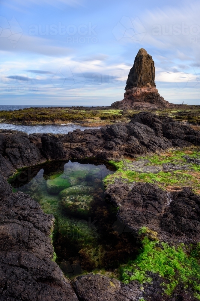 A small pool of water with a rock structure in background - Australian Stock Image