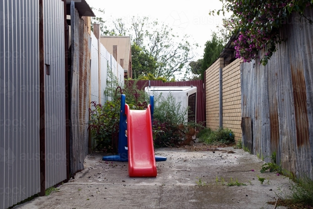 A small red childrens slide in an alleyway - Australian Stock Image