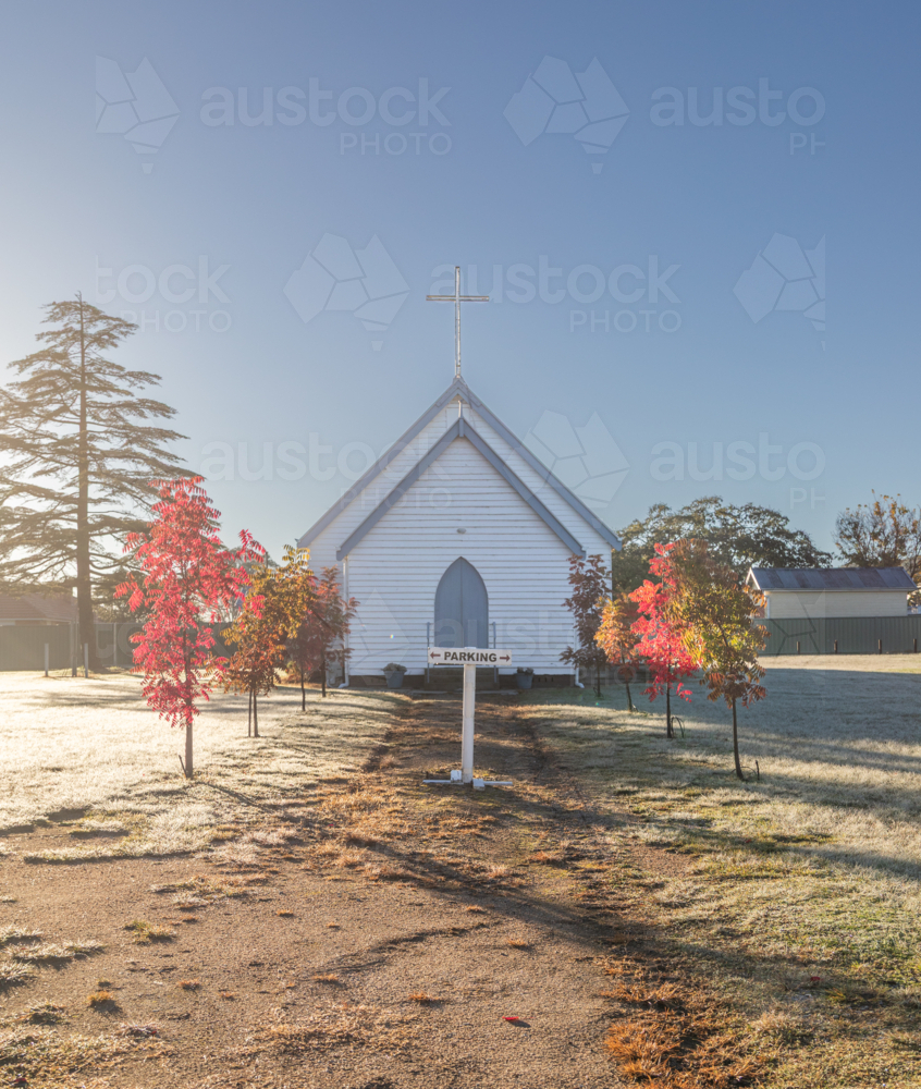 A small white church under a blue sky on an autumn morning - Australian Stock Image