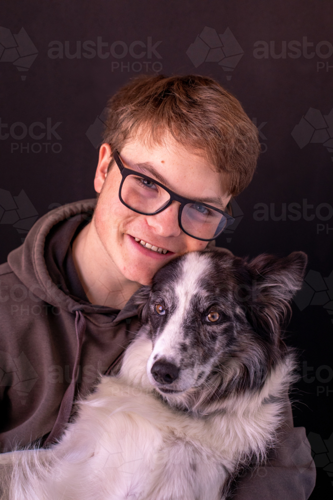 A smiling teenage boy with a black and white dog - Australian Stock Image