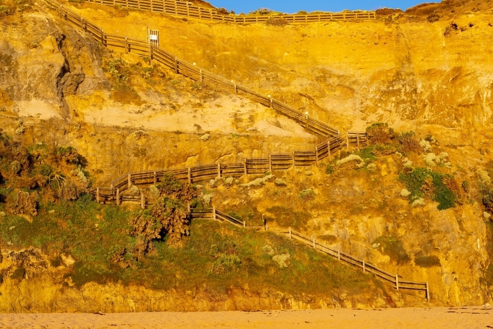 A staircase winding down a steep cliff face the beach below - Australian Stock Image