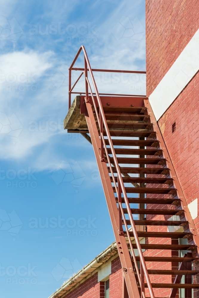 A steel staircase leading up the outside of a brick wall - Australian Stock Image