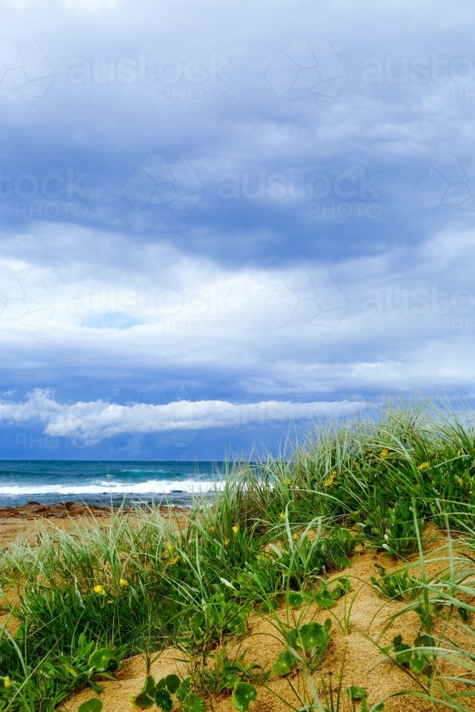 A stormy sky over the dunes and ocean at Sandon Point - Australian Stock Image