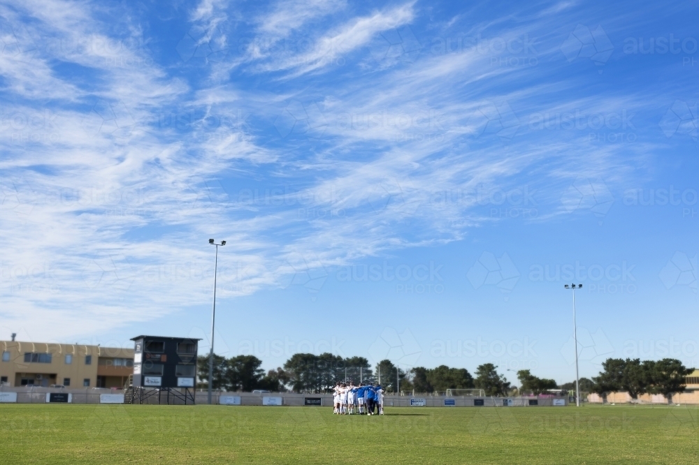 A team huddle seen in the distance on soccer pitch - Australian Stock Image