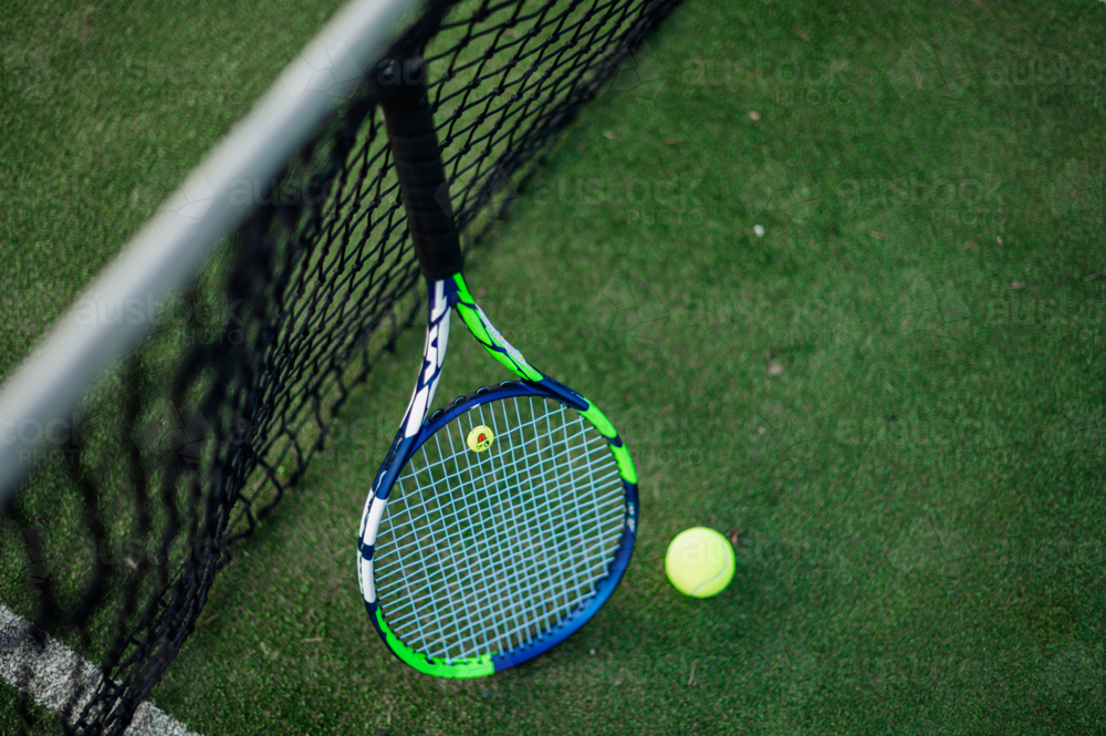 Tennis Racket Against Insaects Image of A tennis racquet leans against the net with a yellow ball ...