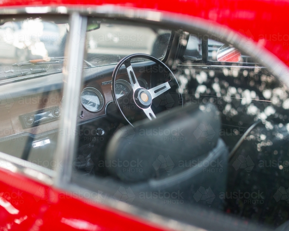 A three spoke steering wheel inside a shiny red car - Australian Stock Image