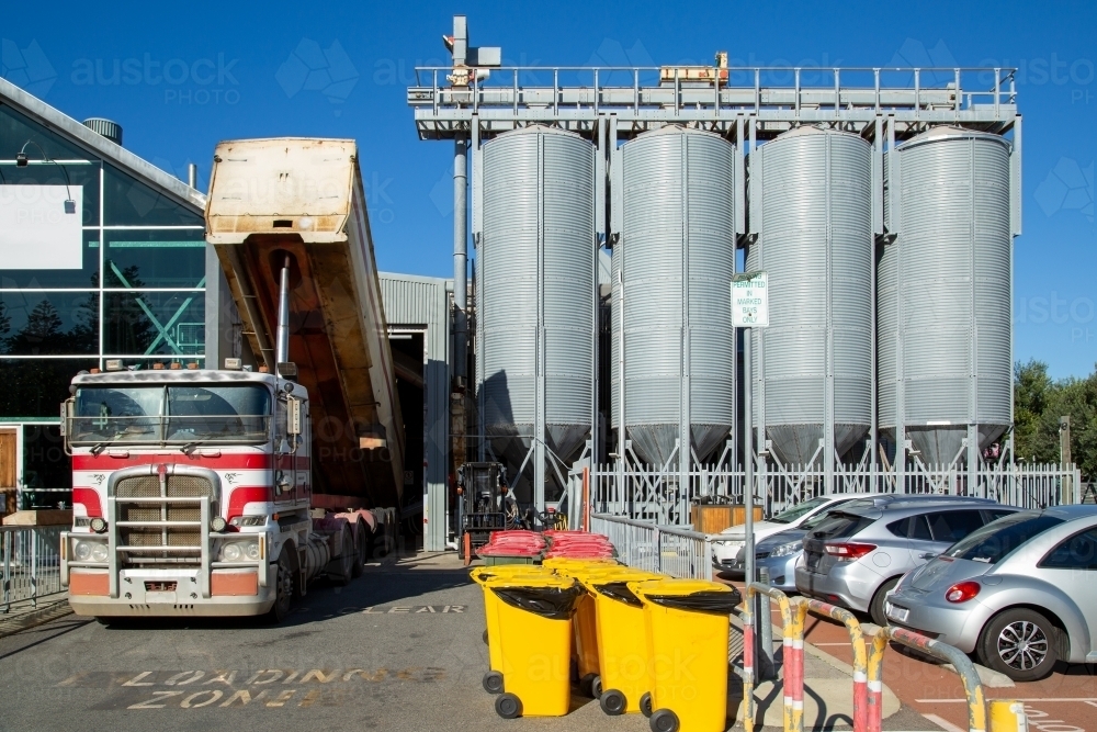 A tip-truck unloads grain at brewery silos. - Australian Stock Image