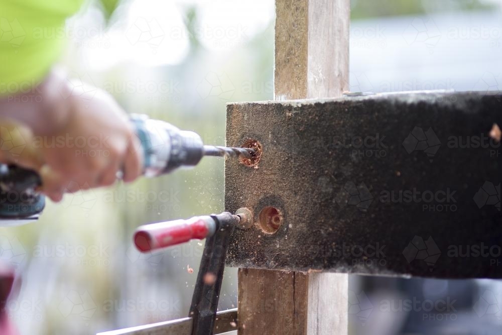 A tradesman drills into a wooden beam. - Australian Stock Image