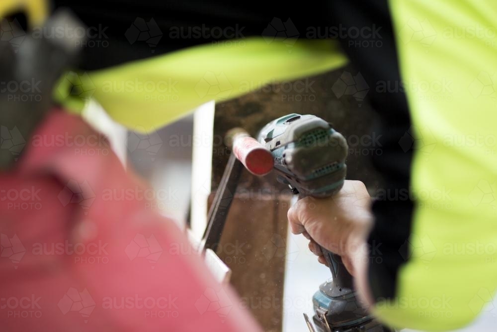 A tradesman drills into a wooden beam. - Australian Stock Image