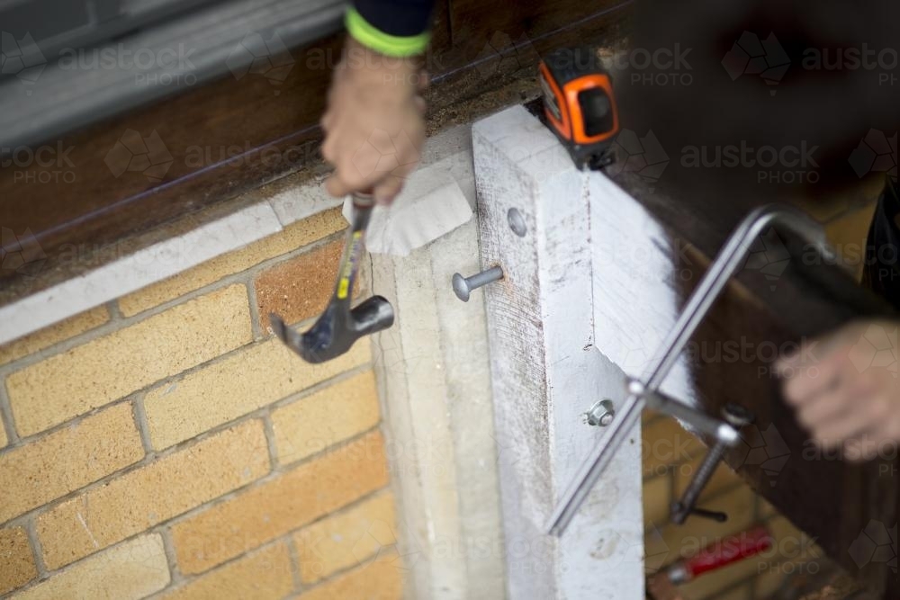 A tradesman hits a bolt into a wooden beam. - Australian Stock Image