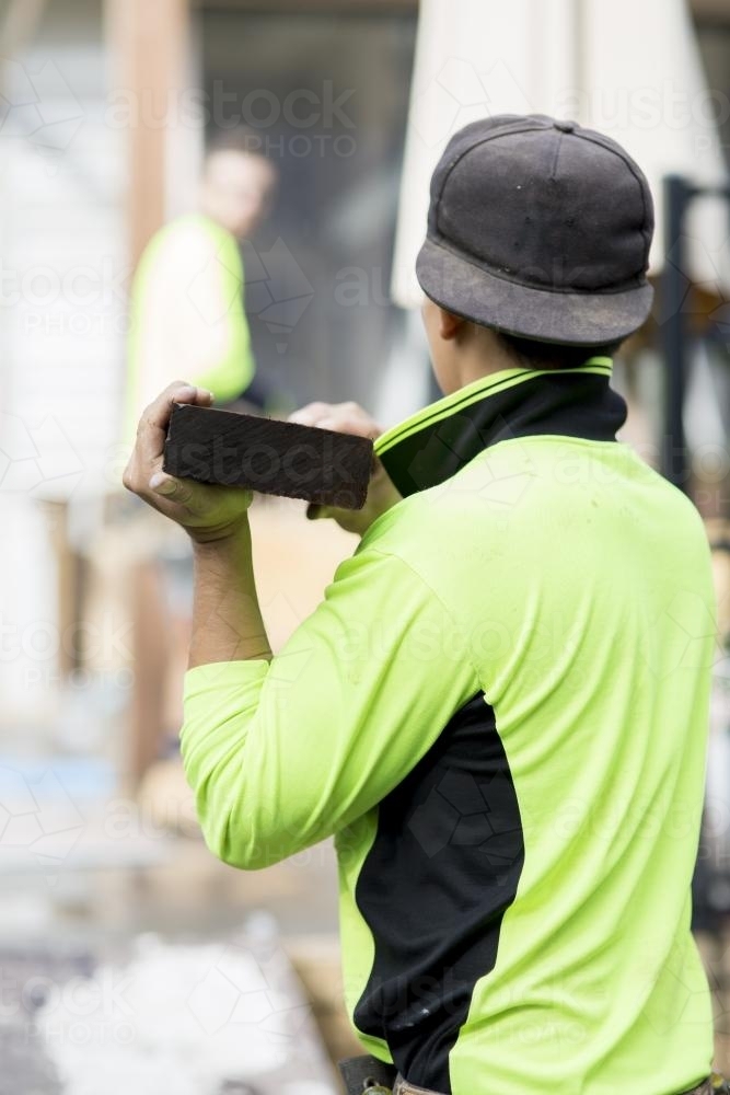 A tradesman lifts a wooden beam. - Australian Stock Image