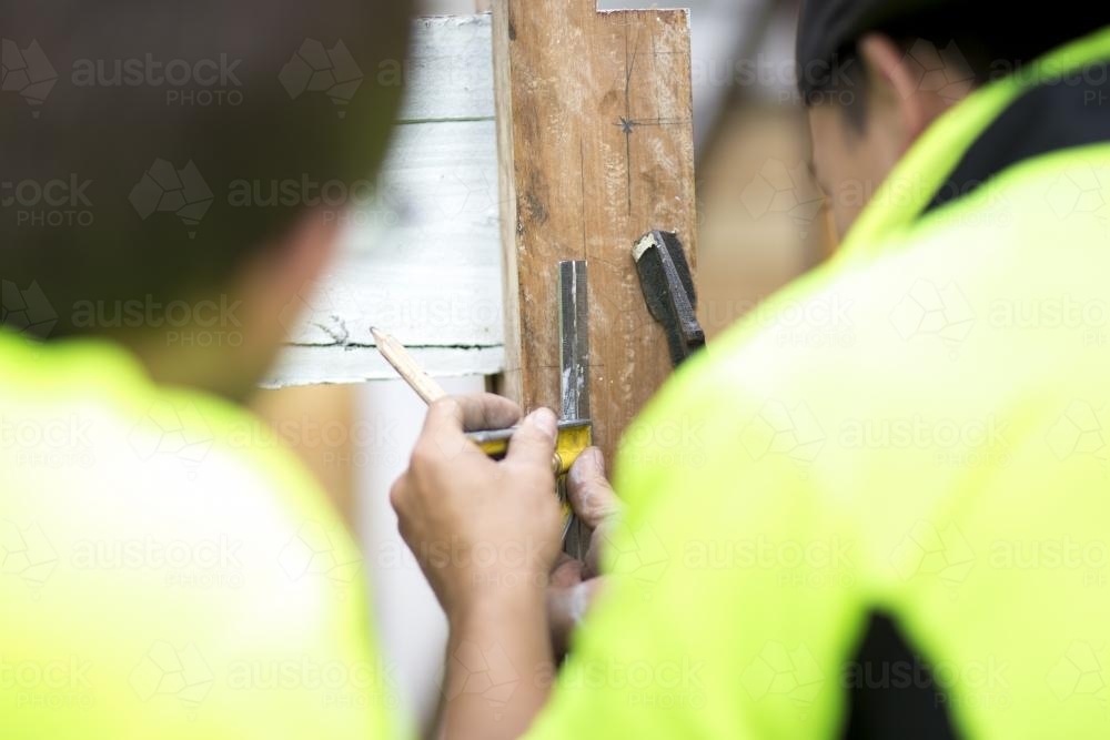 A tradesman marking an angle on a wooden post. - Australian Stock Image