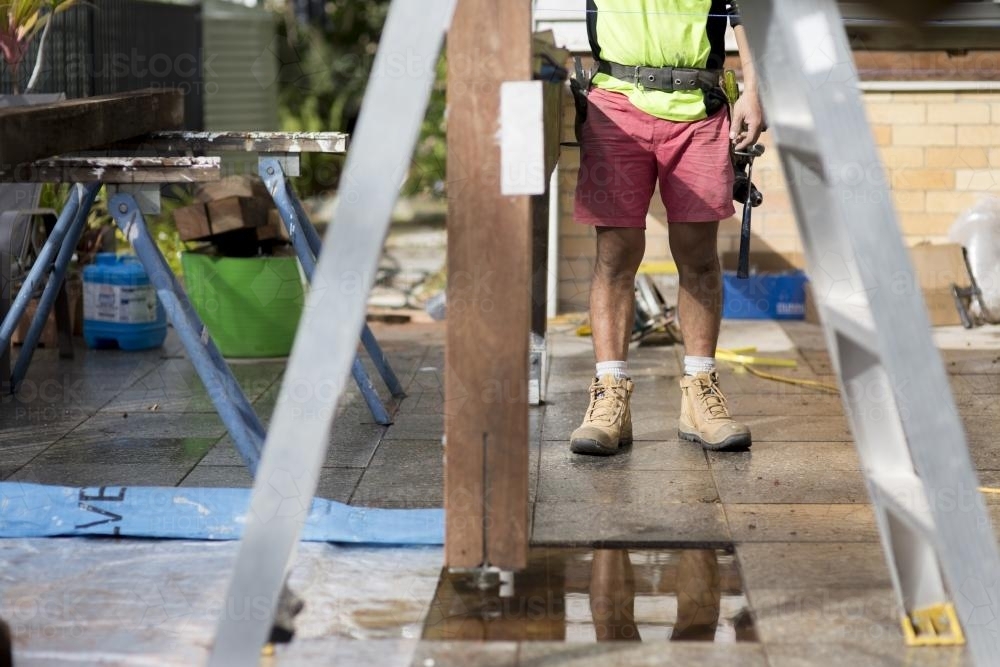 A tradesman standing outside on a home renovation site. - Australian Stock Image