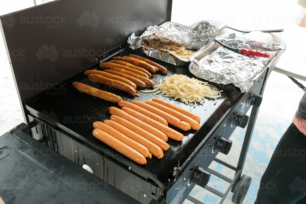A traditional australian bbq sausage sizzle, sausages cooking on a barbeque - Australian Stock Image