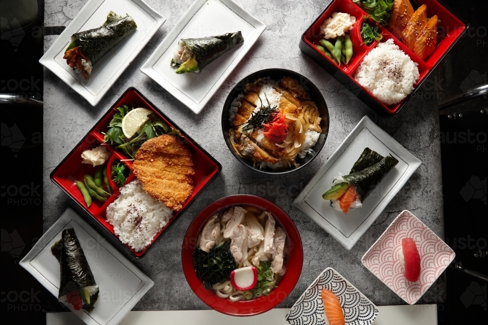 A variety of Japanese dishes in a square and rectangular plates arranged in a marble surface - Australian Stock Image