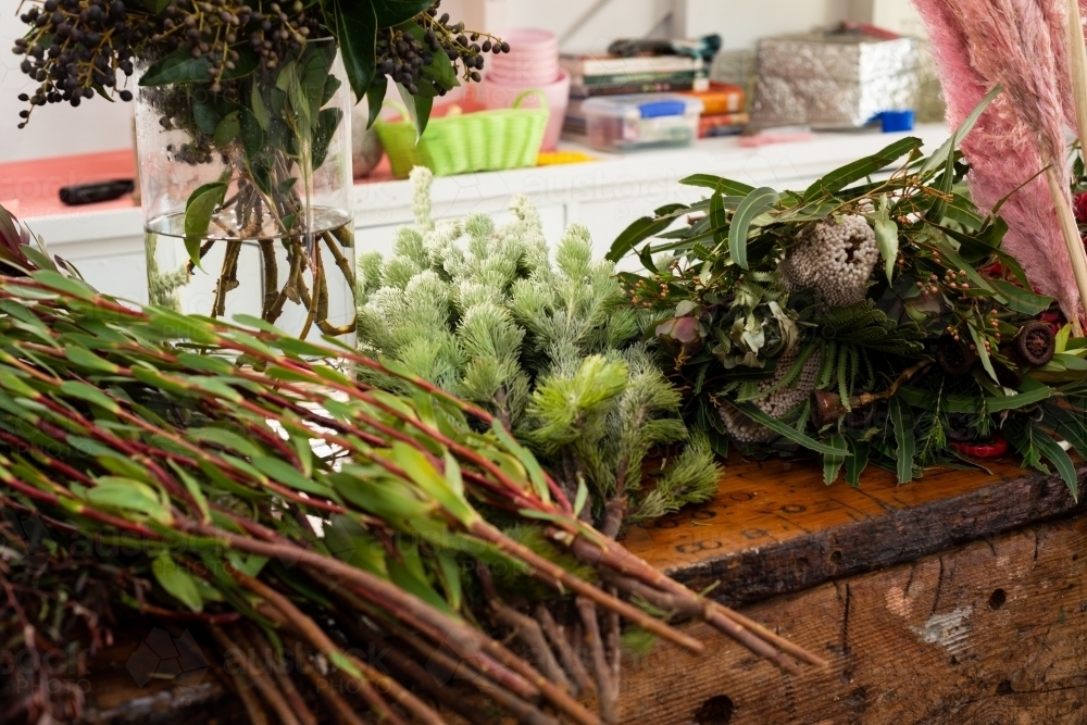 A variety of native and exotic flowers and greenery on a workbench - Australian Stock Image