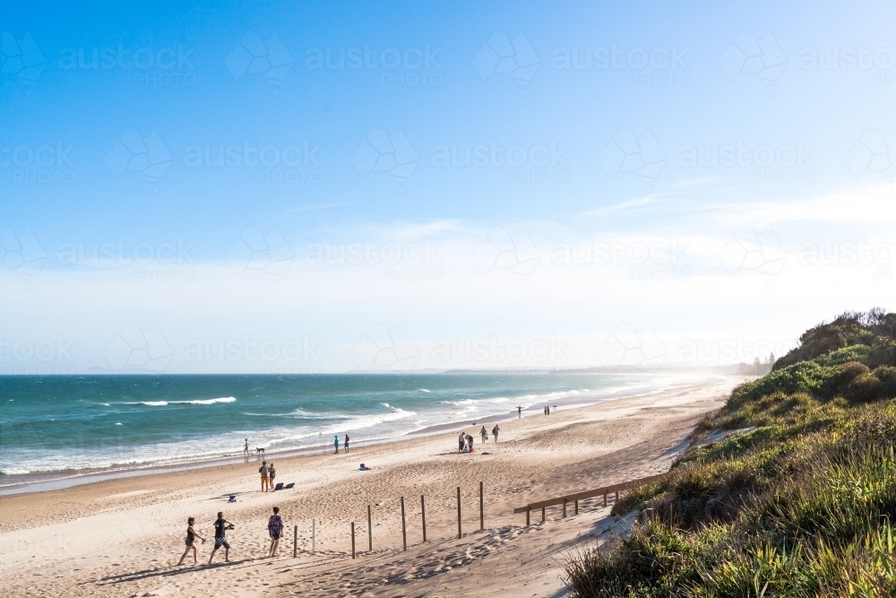 A variety of people and families enjoy a summers day holiday at long beach - Australian Stock Image