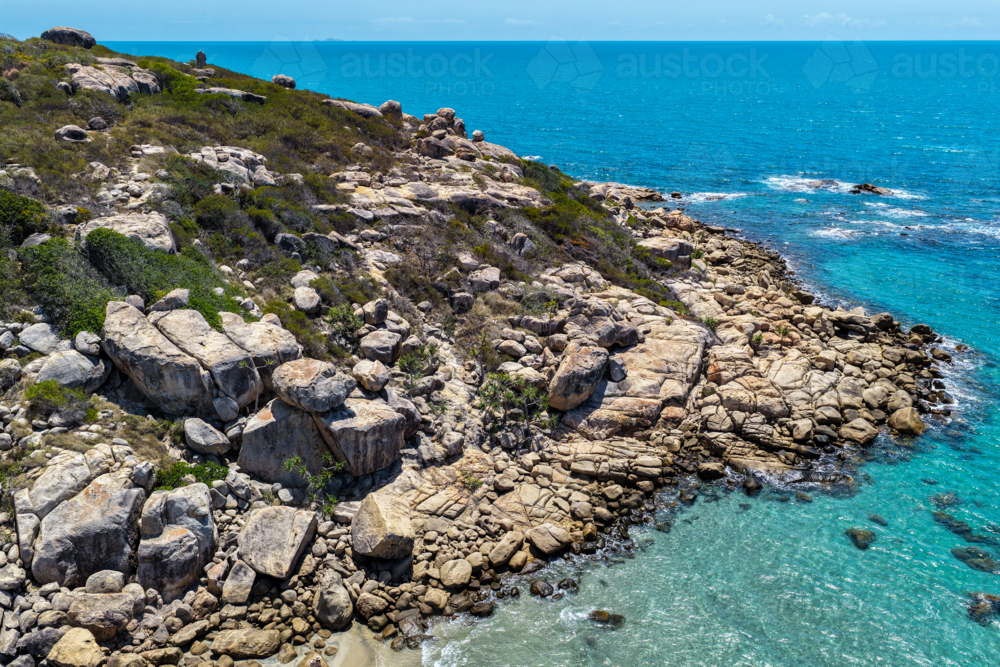 A vibrant aerial view of Rose Bay in Bowen, showcasing its turquoise water and rocky shoreline - Australian Stock Image