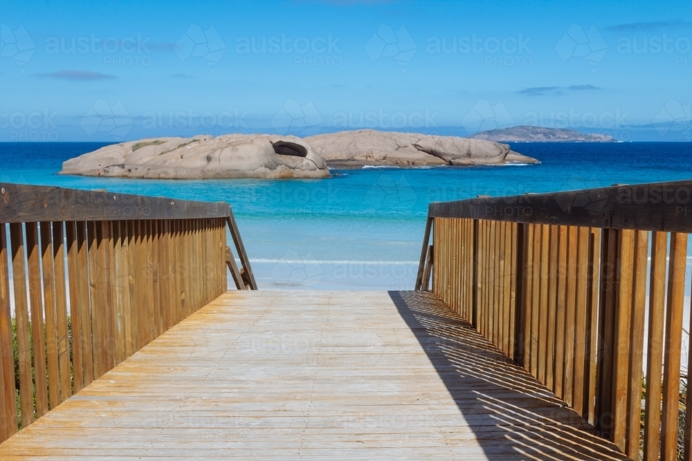 A view of a walkway leading to the blue waters of a beach - Australian Stock Image