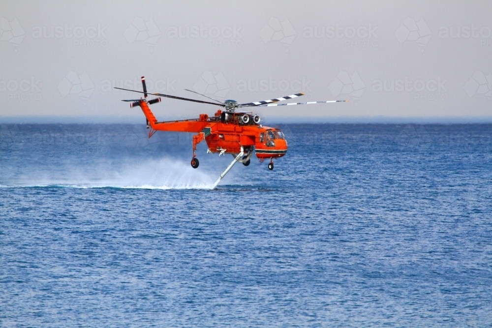 A water-bombing helicopter filling its water tanks from the ocean off Coledale in the Illawarra, NSW - Australian Stock Image