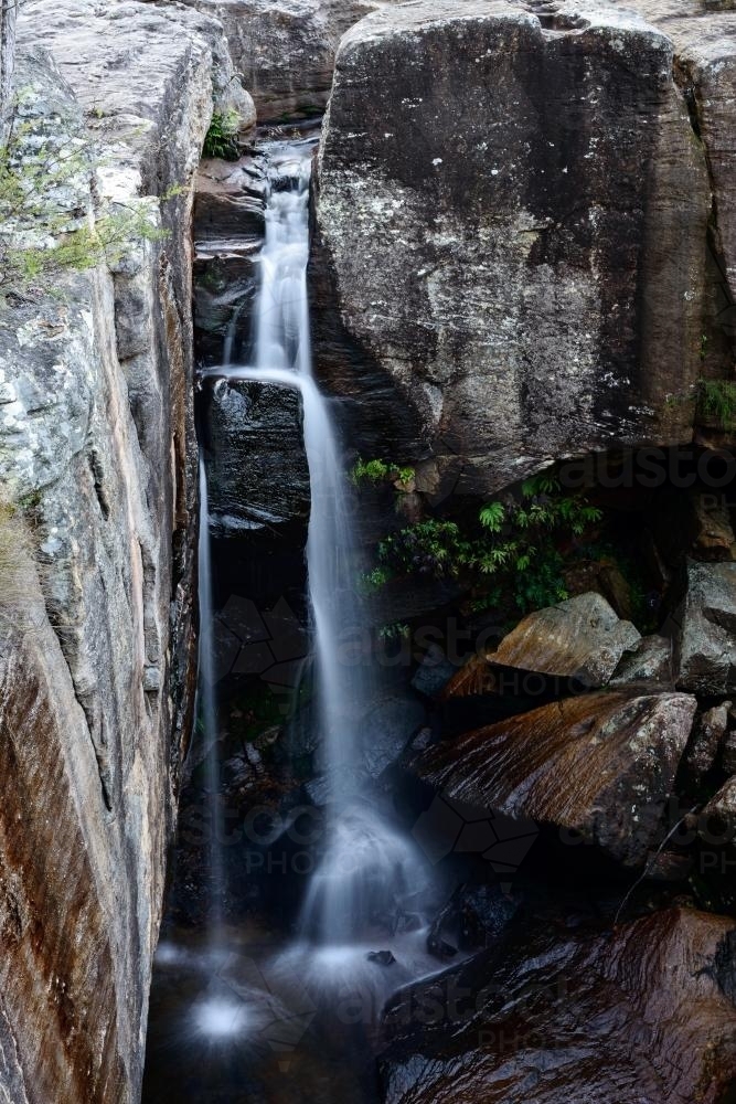 A waterfall plunging between rocks to a pool below - Australian Stock Image