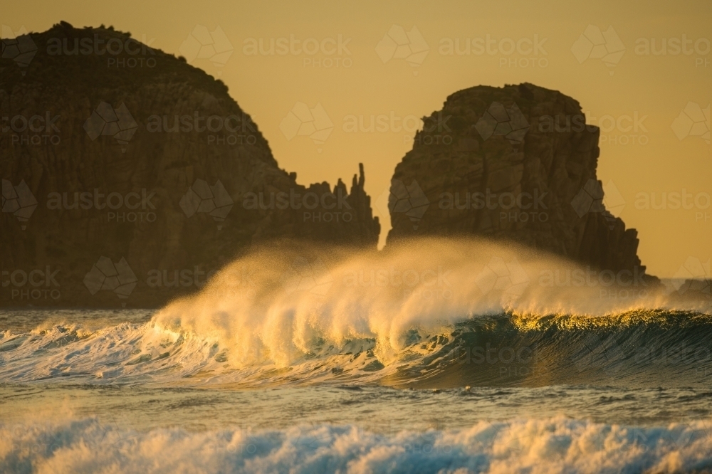 A wave breaks at first light on Woolamai Surf Beach. - Australian Stock Image