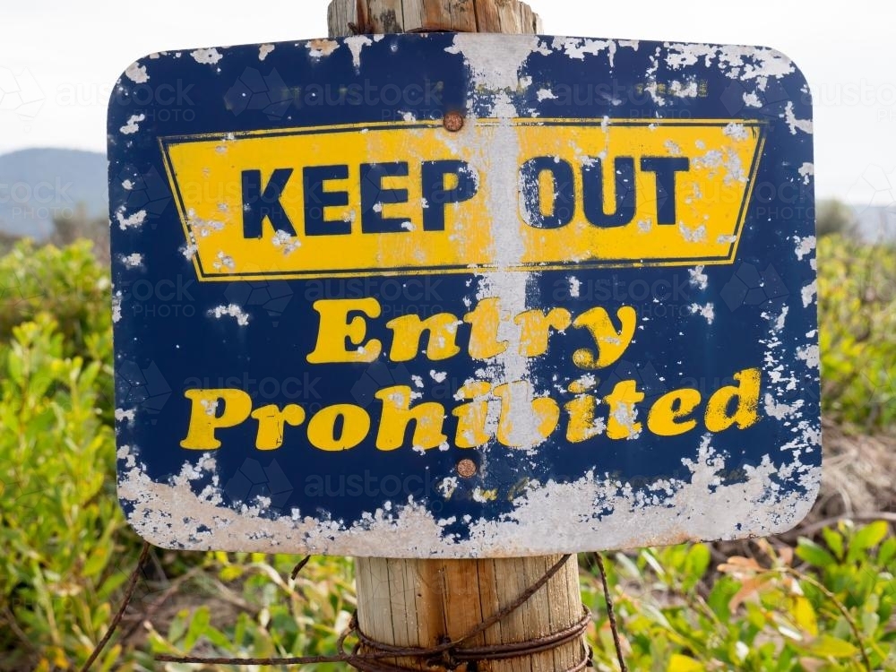 A well worn "KEEP OUT Entry Prohibited" blue and yellow sign - Australian Stock Image