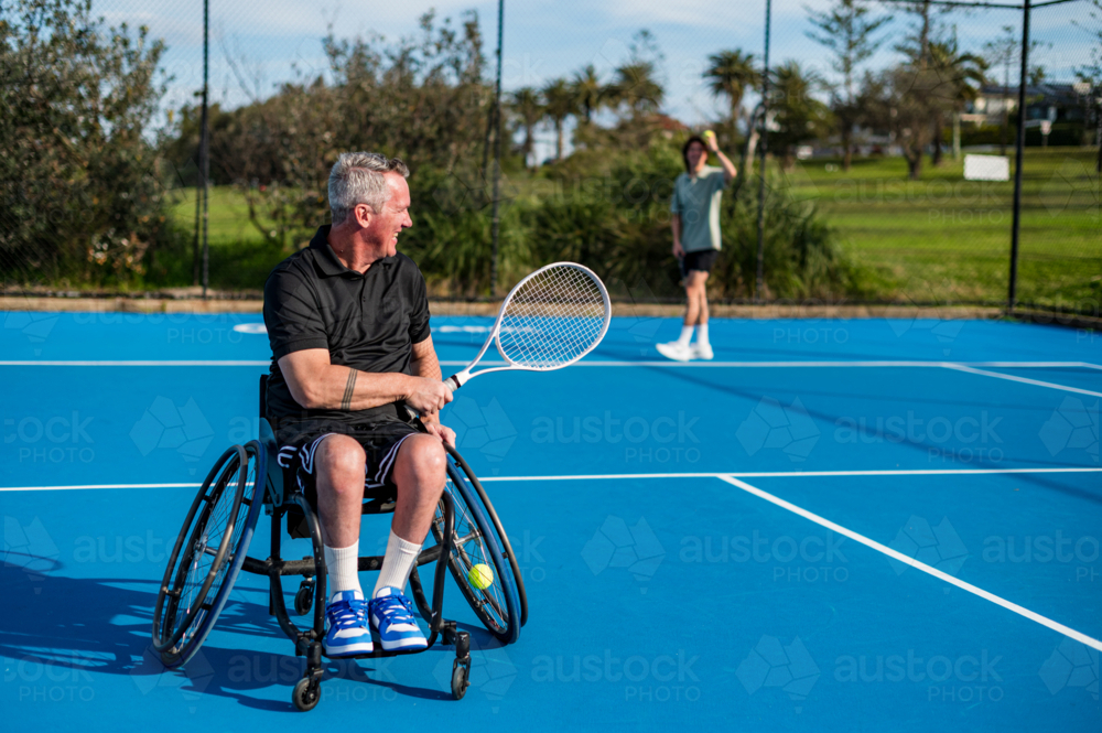 a wheelchair tennis player engage in a competitive match on a bright day at a park - Australian Stock Image