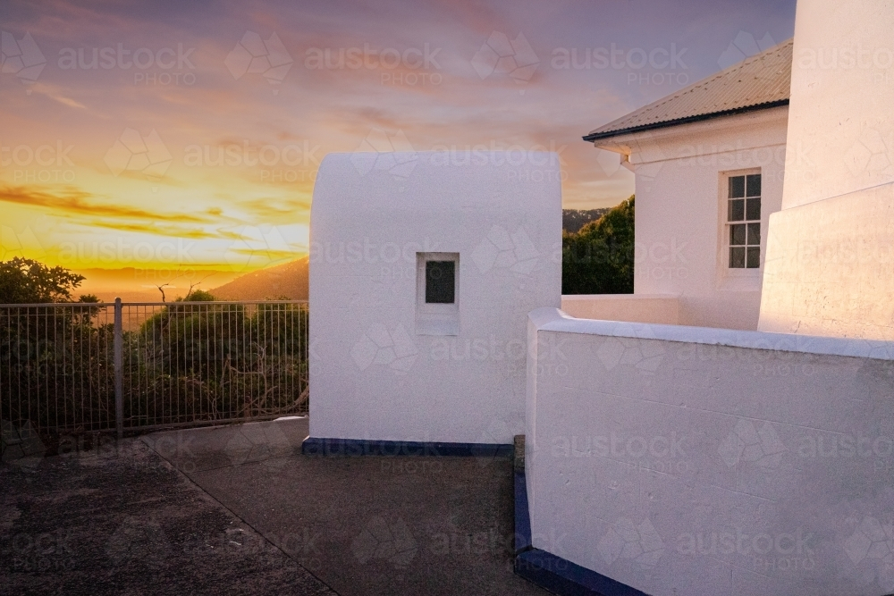 A white building with metal railings with sun setting in the background - Australian Stock Image