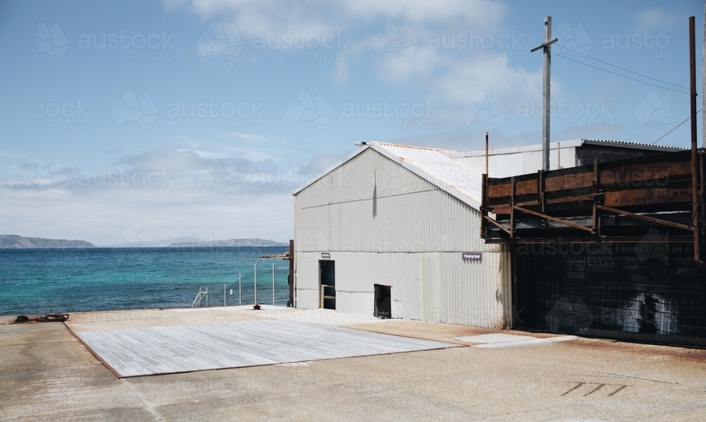 A white warehouse beside the shore at the Old Whaling Station - Australian Stock Image