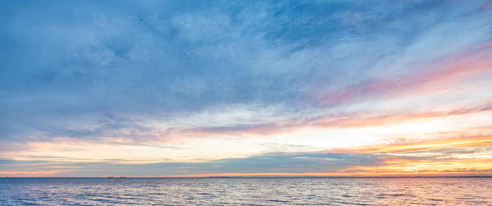 A wide panoramic sky with sunset clouds over ocean - Australian Stock Image