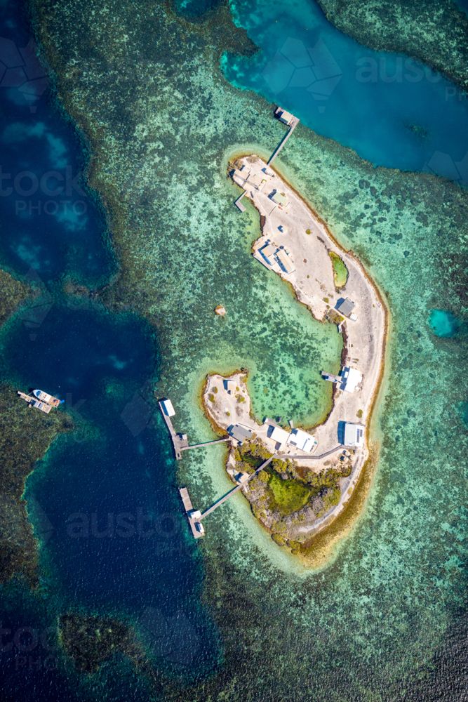 A winding coral cay surrounded by vibrant turquoise shallows and dark reef edges - Australian Stock Image