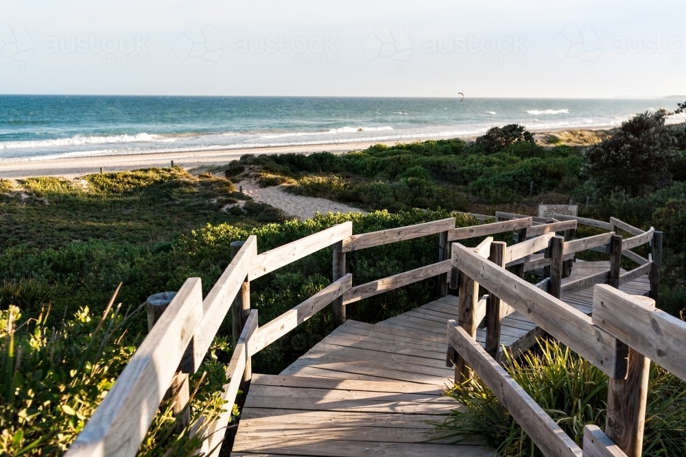 A winding, wooden boardwalk platform providing access to the beach and beach plants - Australian Stock Image