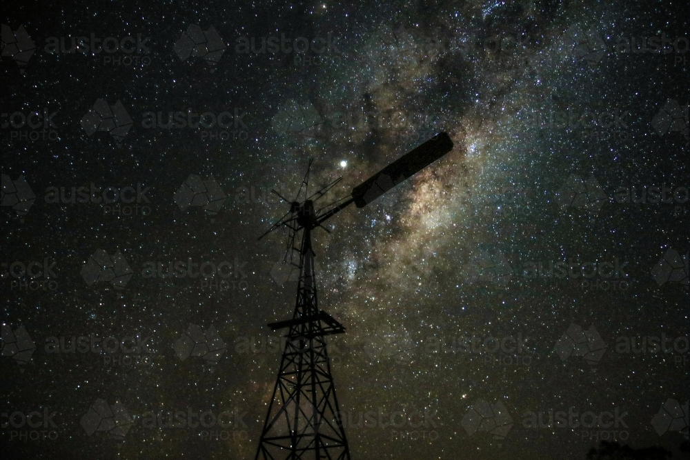 A windmill under a sky filled with stars showcasing a prominent Milky Way galaxy - Australian Stock Image