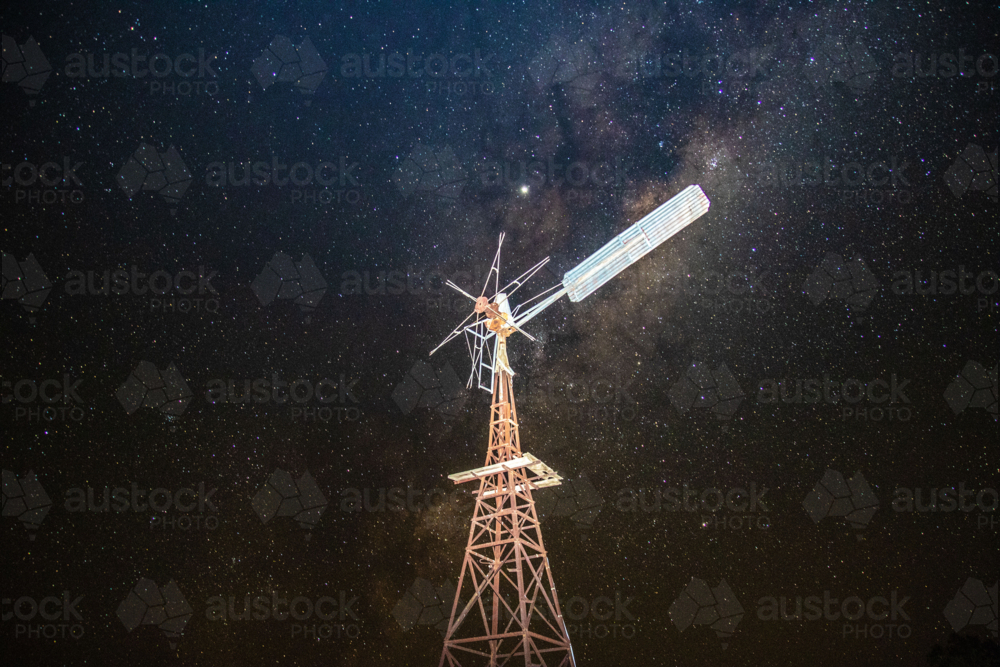 A windmill under a sky filled with stars showcasing a prominent Milky Way galaxy - Australian Stock Image