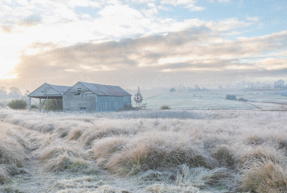 A winter's scene with a frosty field, an old hay shed and a broken windmill - Australian Stock Image
