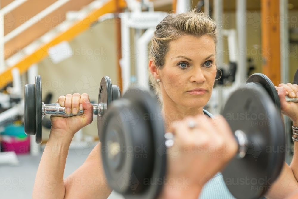 A woman lifting weights in a gym mirror - Australian Stock Image