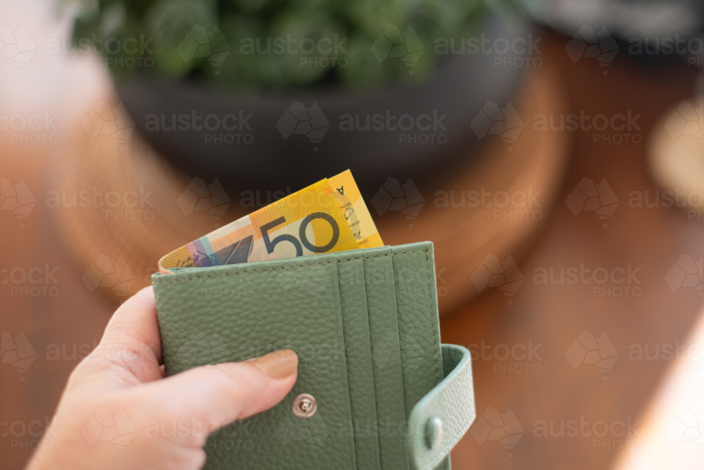 a woman's hand holding a simple green wallet with Australian money sticking out. - Australian Stock Image