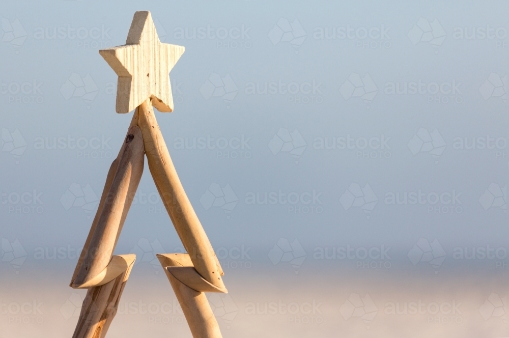 A wooden Christmas tree against a beach background with copy space. - Australian Stock Image