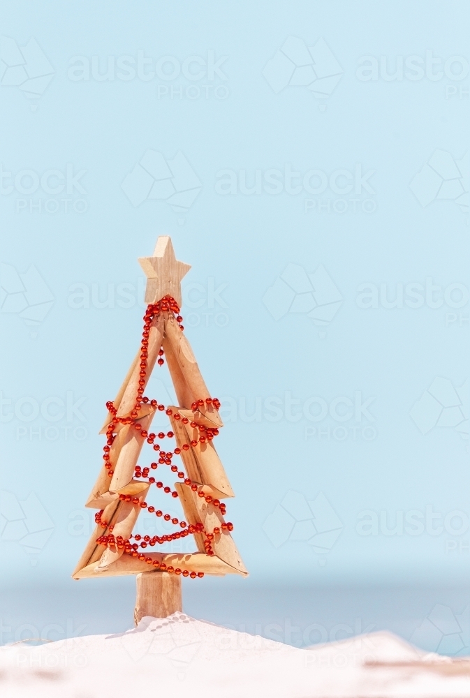 A wooden Christmas tree decorated with red baubles stands on the beach in Australia - Australian Stock Image