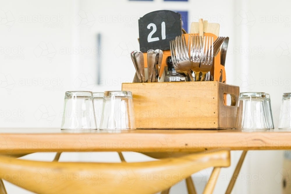 A wooden table in a restaurant with cutlery and glasses sitting on it - Australian Stock Image