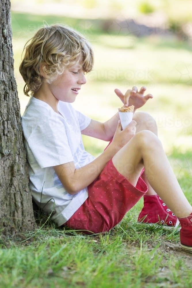 A young boy poking his finger into an ice cream cone - Australian Stock Image
